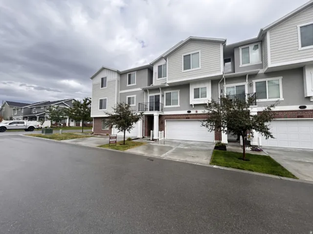 Three-story townhome with a two-car garage, brick accents, and a second-story balcony