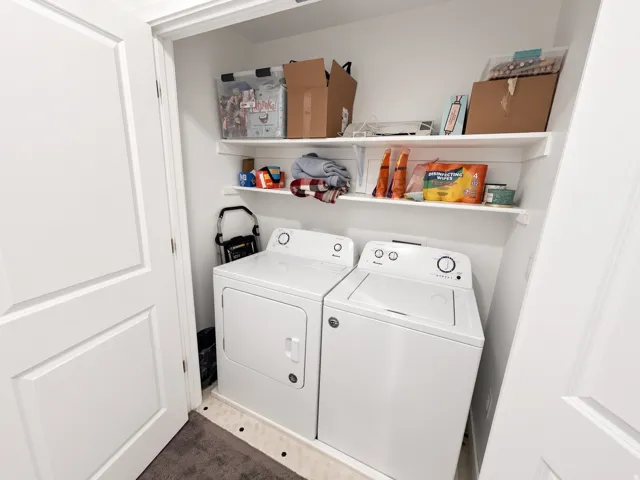 Dedicated utility space featuring a washer and dryer, two built-in storage shelves, and solid panel doors