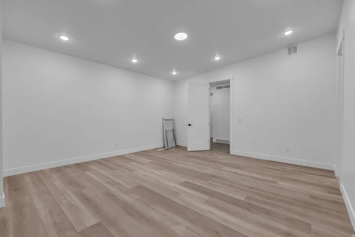 Recessed lighting illuminates wood-finish flooring, white walls, and white trim