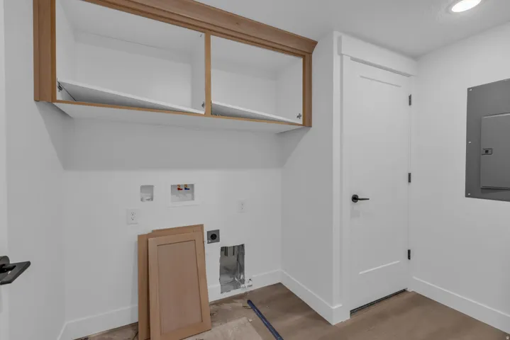 Upper cabinetry with wood-finish trim, a white paneled door with matte black hardware, and wood-finish flooring