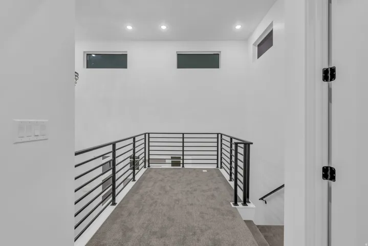 White walls featuring contemporary bar-style railings, recessed lighting, and high transom windows