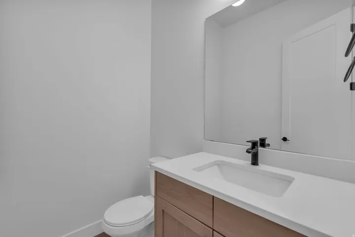 Bathroom featuring a wood-finish vanity with an integrated sink, a white countertop, and a matte black faucet