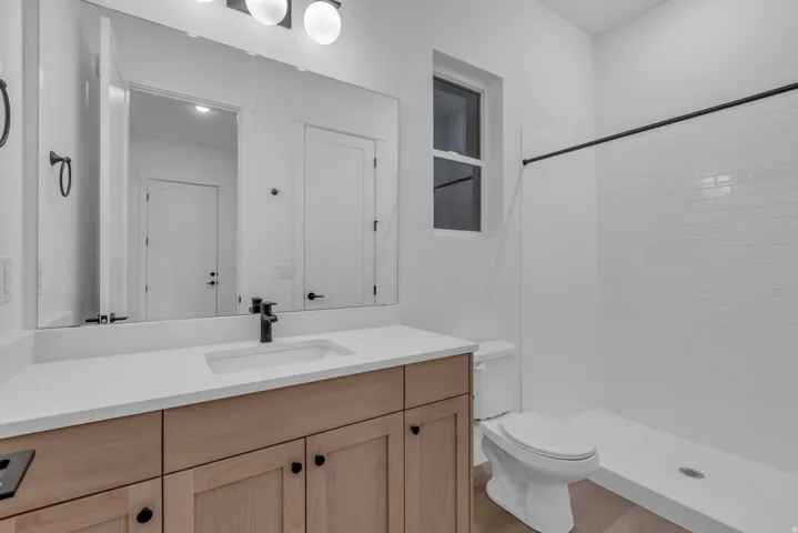 Floating wood-finish vanity with a rectangular basin sink, matte black faucet, and white countertop