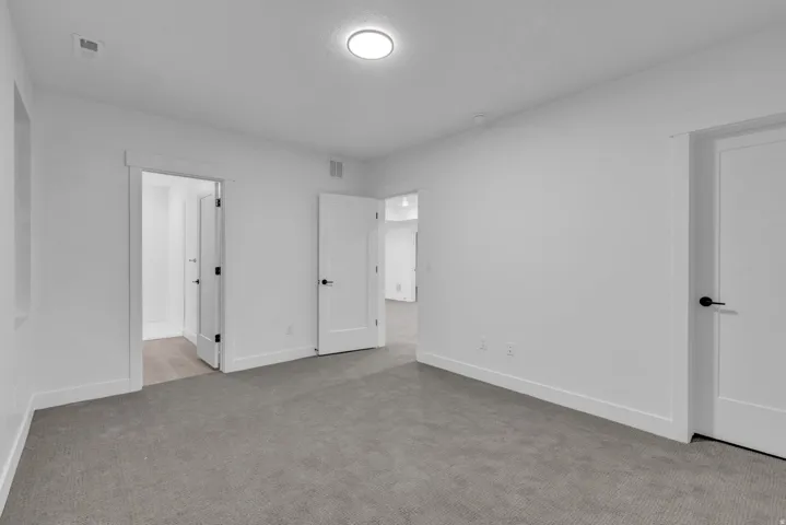 Recessed ceiling light fixture, white walls, gray carpet flooring, white trim, and white interior doors with black hardware
