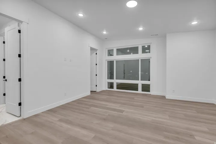 Expansive room featuring wood-finish flooring, recessed lighting, and a multi-pane window