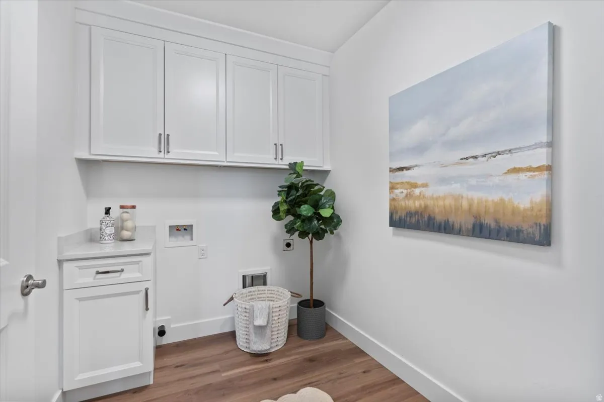 White shaker-style cabinetry with chrome hardware, wood-finish flooring, and a stone-look countertop