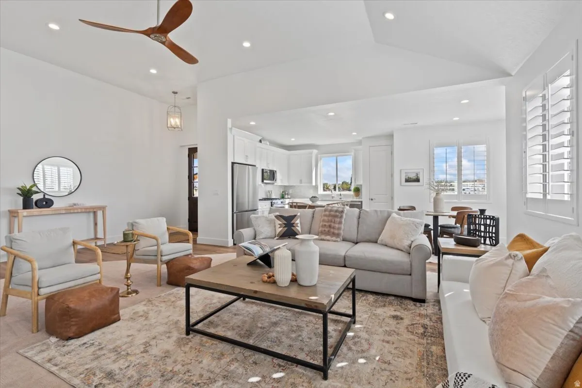 Vaulted ceiling, recessed lighting, wood-finish flooring, wood blade ceiling fan, and white plantation shutters
