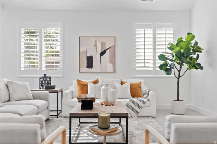 White walls, light-colored flooring, and two windows with white plantation shutters