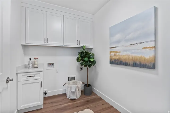 White shaker-style cabinetry with chrome hardware, wood-finish flooring, and a stone-look countertop