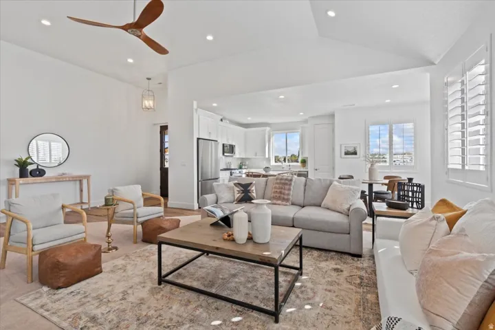 Vaulted ceiling, recessed lighting, wood-finish flooring, wood blade ceiling fan, and white plantation shutters