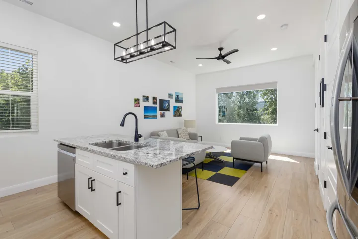 Open-concept living area with wood-finish flooring, recessed lighting, and a modern ceiling fan