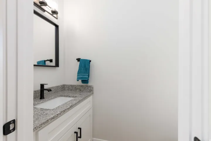 White vanity with black hardware, stone-finish countertop, undermount sink, and matte black faucet