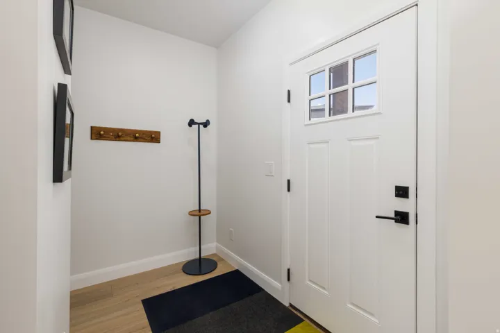 Entryway featuring a white paneled door with divided lite windows, matte black hardware, and wood-finish flooring
