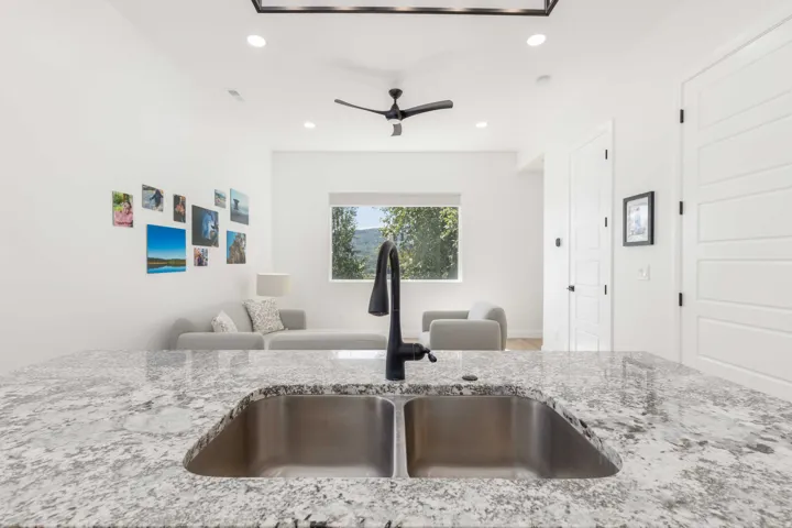 Kitchen island featuring a dual stainless steel sink, speckled countertop, and matte black faucet