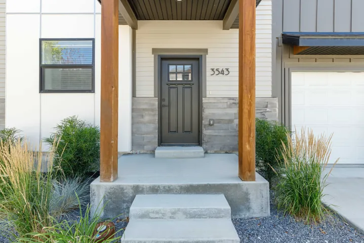 Covered entry with wood-finish support beams and stone veneer accents
