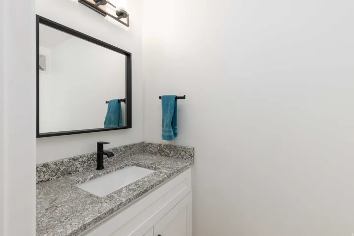 White vanity with an undermount sink, speckled countertop, and matte black faucet
