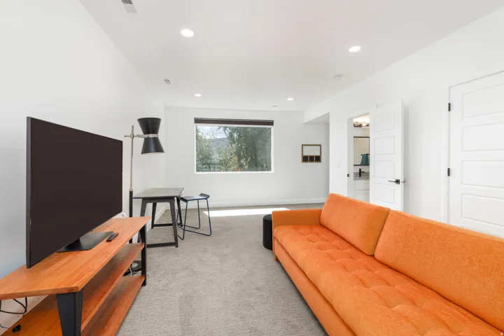 Recessed ceiling lighting, white interior doors with contemporary hardware, a large picture window, and neutral carpeting