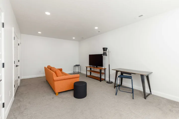 Recessed ceiling lighting, white interior doors with dark hardware, light gray carpet, and white walls