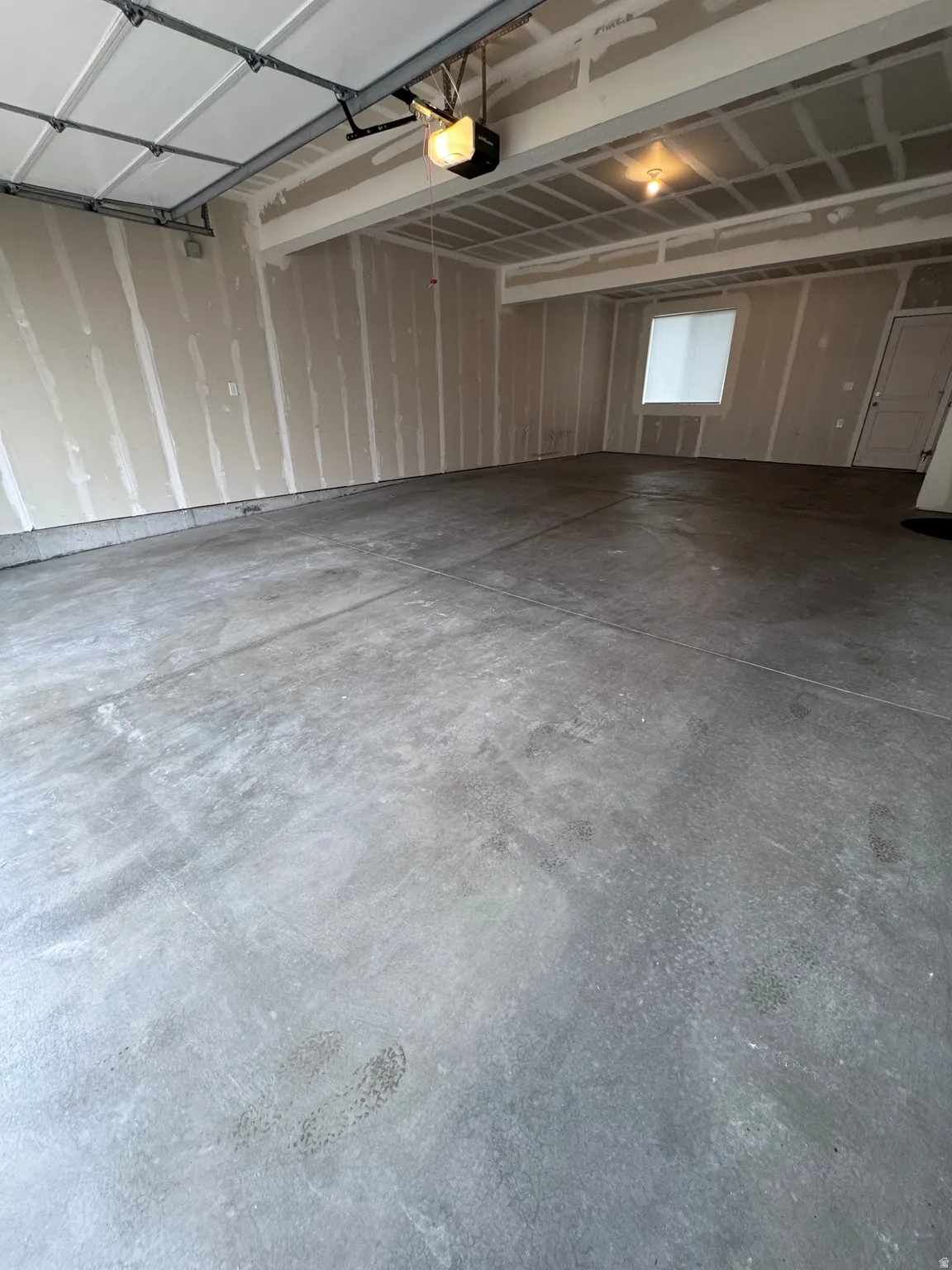 Concrete floor with an overhead garage door, automatic opener, and a window