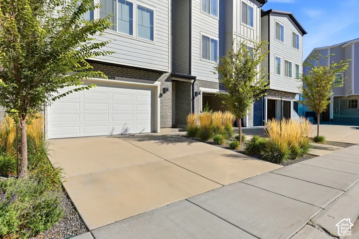 Modern townhome exterior with horizontal siding, brick accents, and a panel garage door