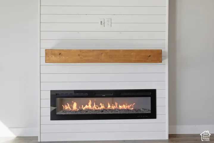 Shiplap accent wall featuring a built-in linear fireplace and wood mantle