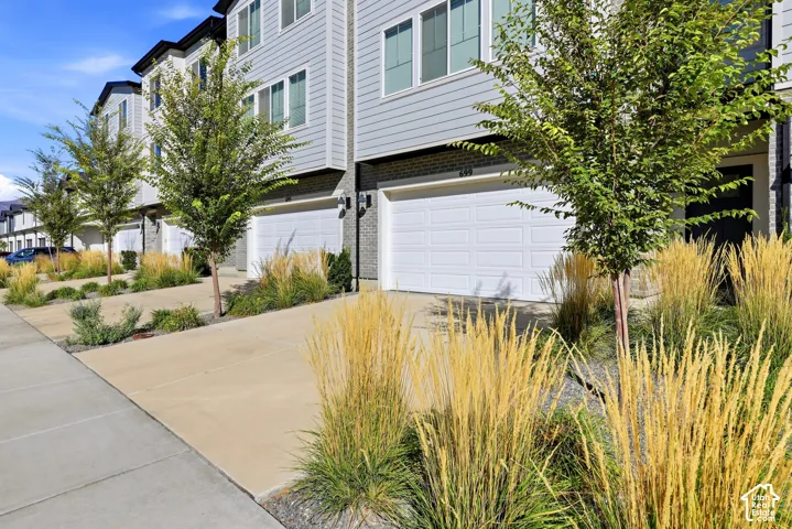 Contemporary townhome with light gray siding, dark trim accents, and a white garage door