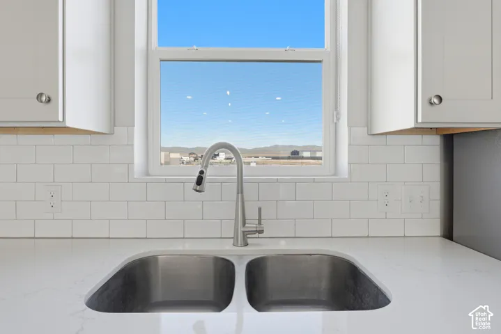 Dual basin stainless steel sink with a high-arc pull-down faucet, set into a light-toned countertop