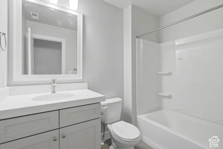 Bathroom featuring a single vanity with an integrated sink, framed mirror, and a full bathtub with shower surround