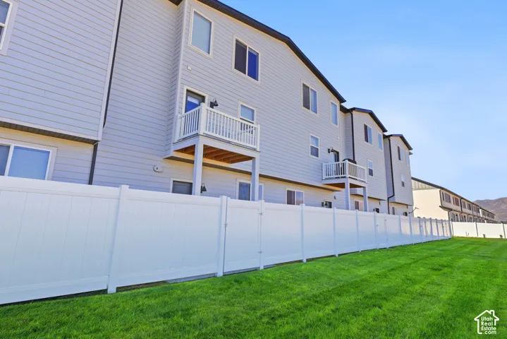 Expansive green space featuring a white privacy fence, light gray exterior siding, and multiple private balconies