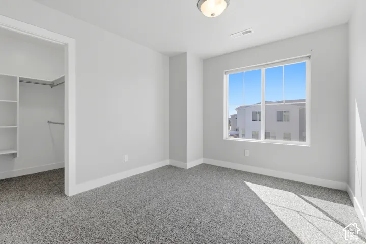 Light gray walls with white trim, gray carpet, and a built-in closet system