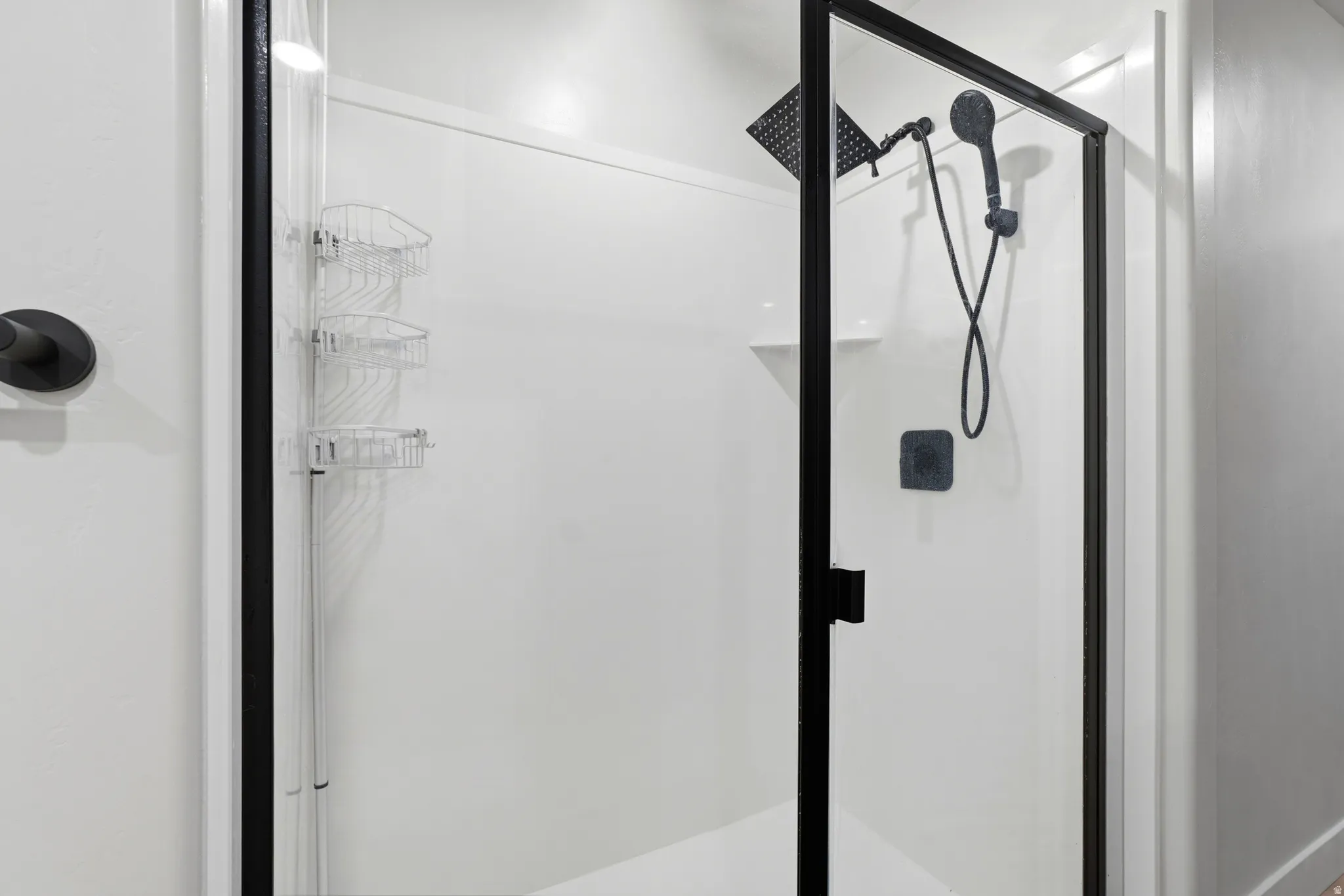 Walk-in shower with clear glass enclosure and matte black framing