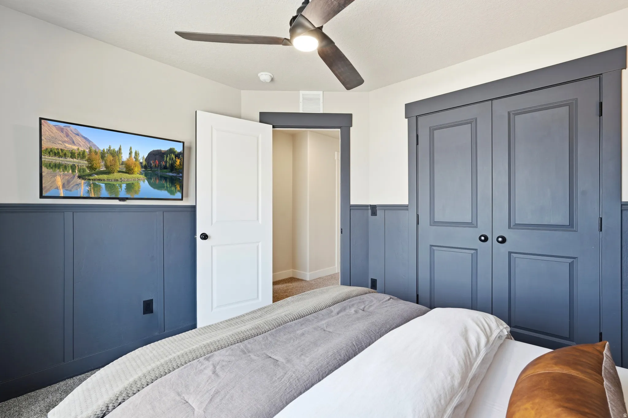 Built-in wall paneling, ceiling fan, carpeted flooring, and paneled closet doors