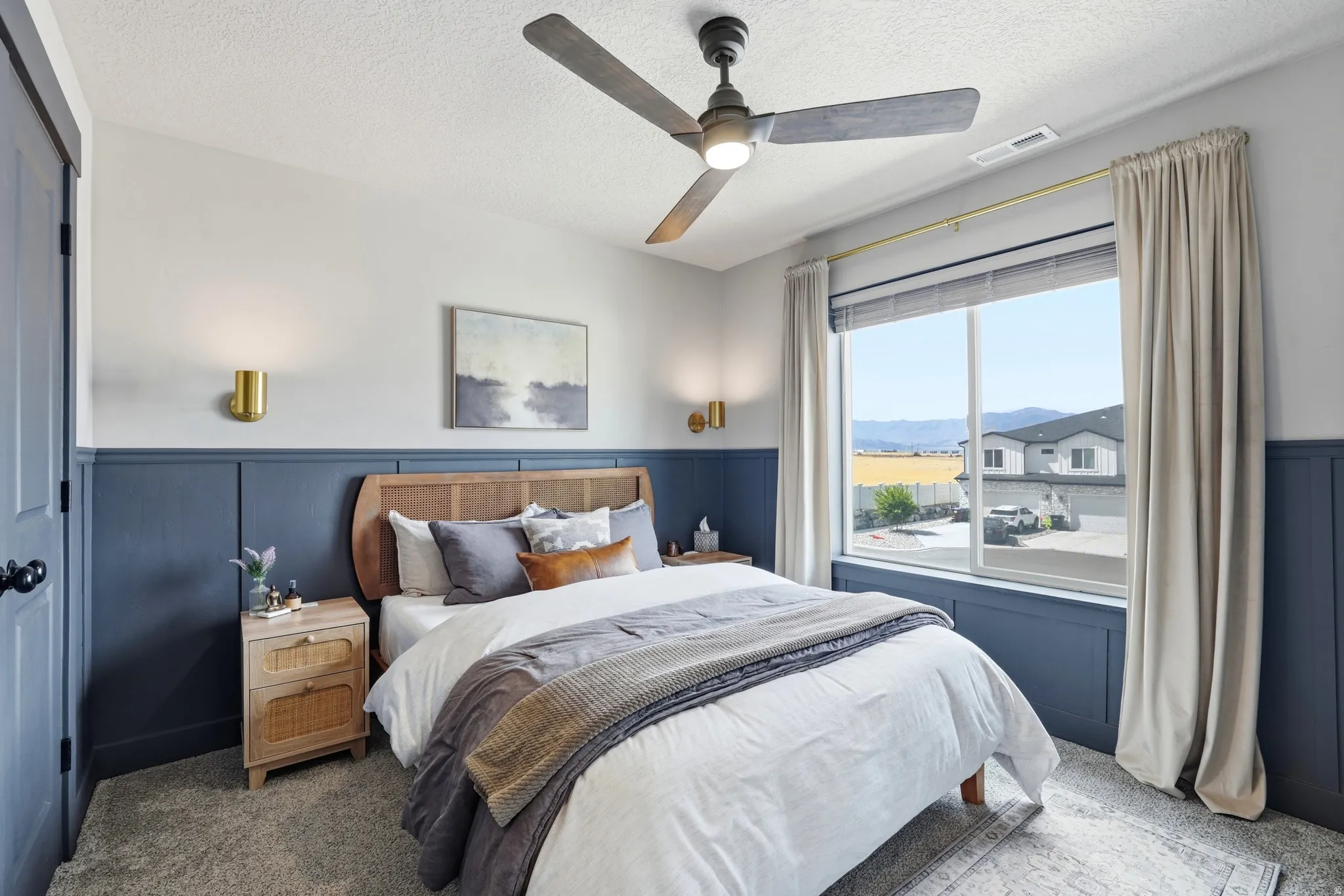 Bedroom featuring a ceiling fan, wall-mounted sconces, and a large window