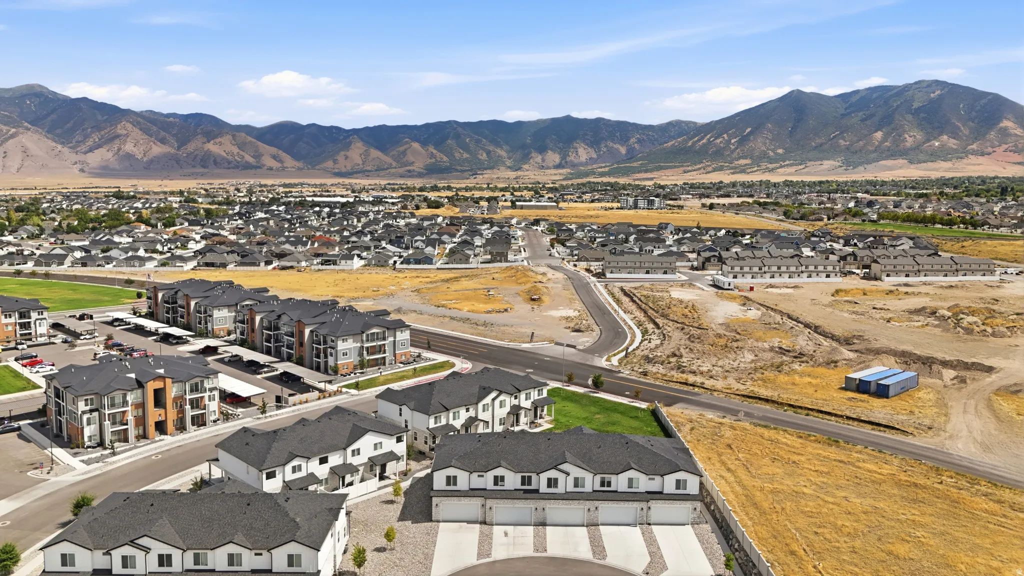 Expansive residential development with mountain backdrop, multiple newly constructed buildings, and paved roads