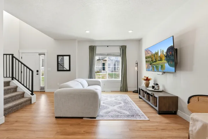 Vaulted ceiling, wood-finish flooring, recessed lighting, and a white front door with a sidelight