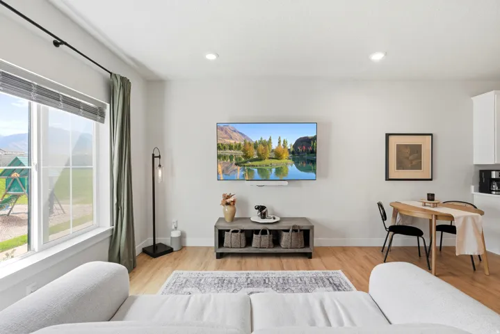 Recessed lighting, wood-finish flooring, white walls, and a built-in kitchen cabinet