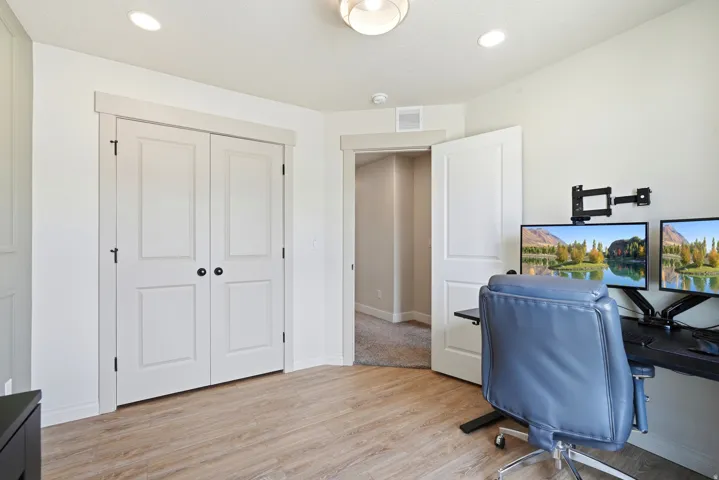 Light wood-finish flooring, recessed lighting, white interior doors, and a neutral wall color