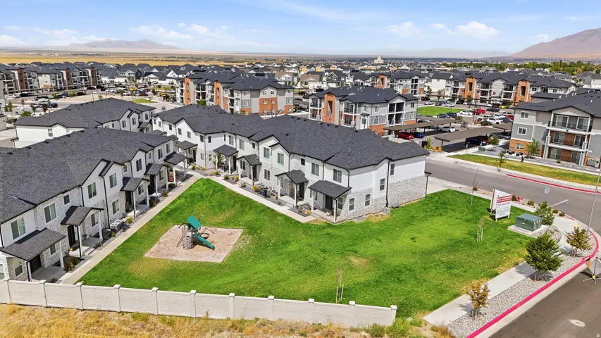 Residential development with multiple townhome-style buildings, green spaces, and mountain backdrop