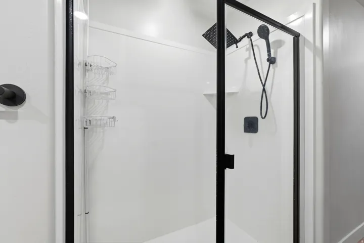 Walk-in shower with clear glass enclosure and matte black framing