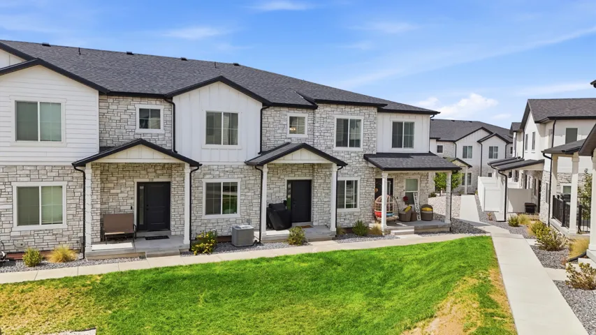Stone and siding exterior with black window frames, covered entryways, and dark shingle roofing