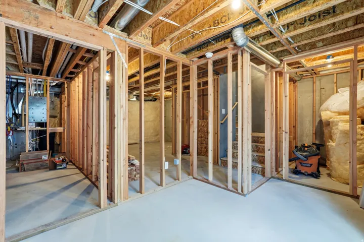 Unfinished basement with concrete flooring, exposed wood framing, and visible utility infrastructure