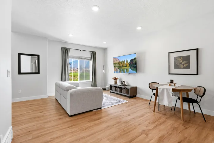 Open-concept living space with wood-finish flooring, recessed lighting, and ample natural light from a large window