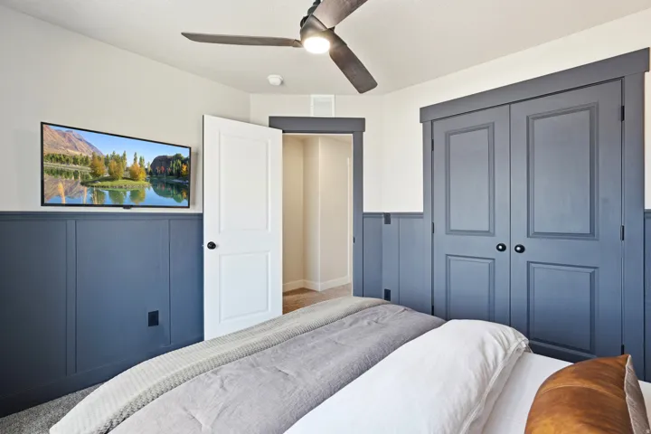 Built-in wall paneling, ceiling fan, carpeted flooring, and paneled closet doors