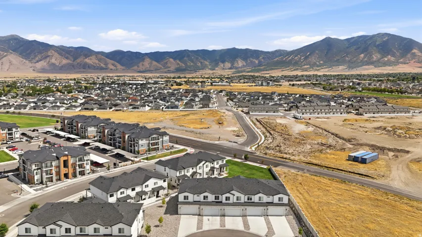 Expansive residential development with mountain backdrop, multiple newly constructed buildings, and paved roads