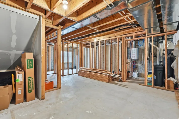 Unfinished basement with exposed wood framing, concrete flooring, and exposed ceiling joists