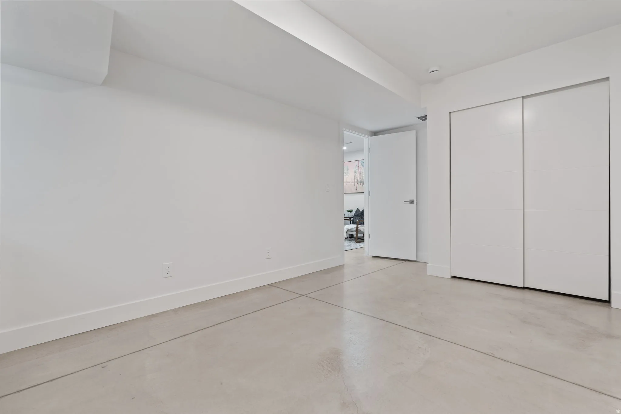 Polished concrete flooring, crisp white walls, and built-in closet with sliding doors
