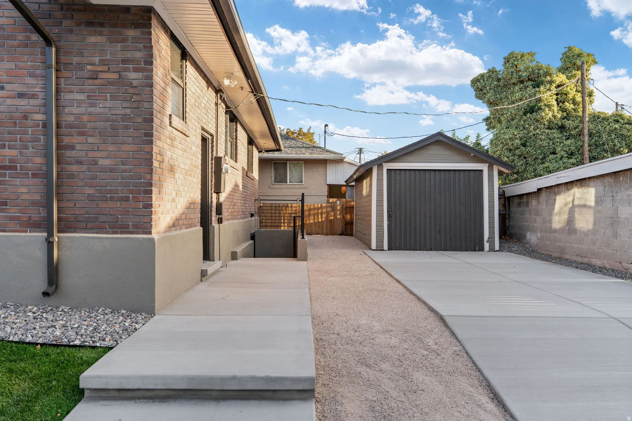 Brick exterior with a detached garage, concrete driveway, and concrete block wall