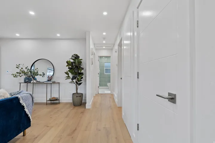 Wood-finish flooring throughout, recessed lighting, and contemporary white doors with dark hardware