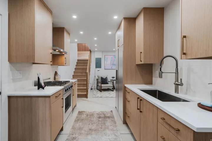Contemporary kitchen featuring wood-finish cabinetry, stainless steel appliances, a gas range with an exhaust hood, and a deep basin sink