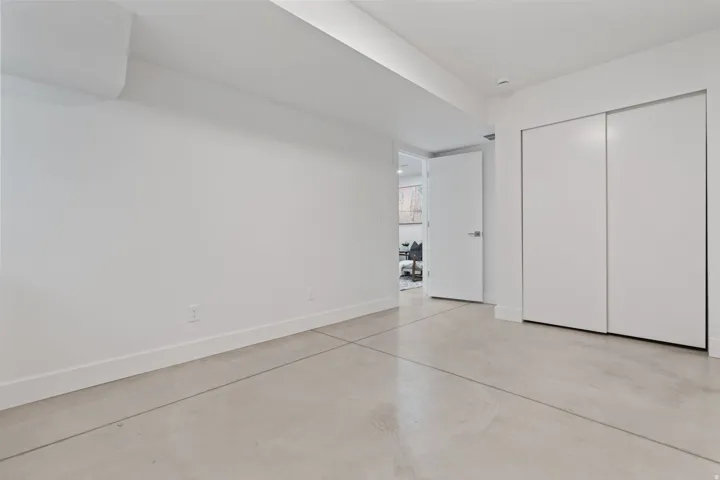 Polished concrete flooring, crisp white walls, and built-in closet with sliding doors